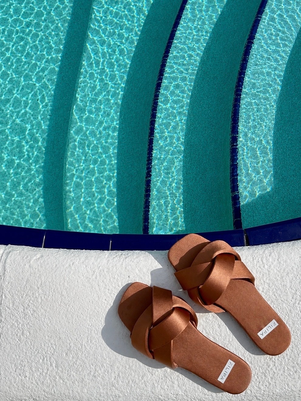 Brown sandals styled on a white pool deck